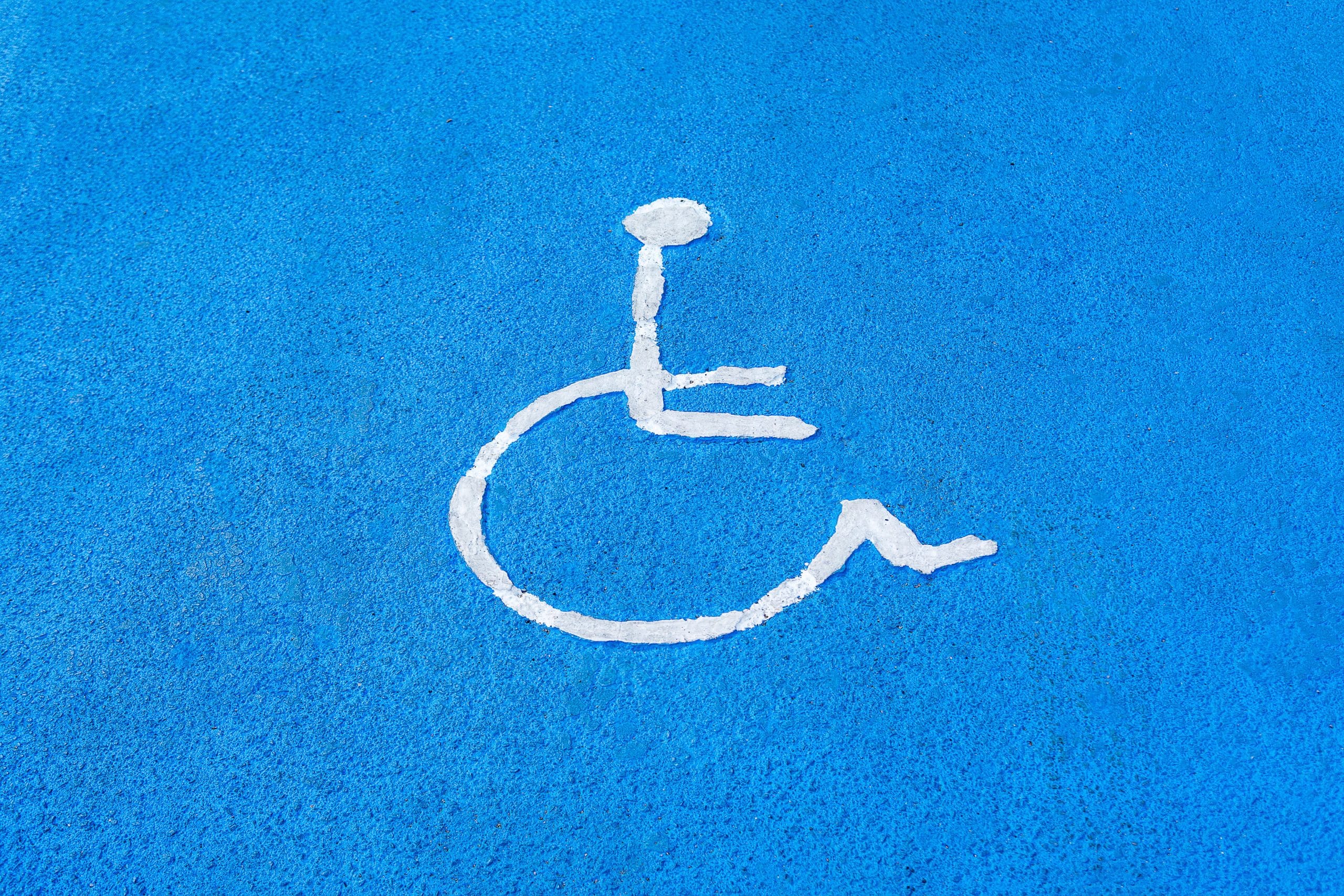 Clear blue disabled parking sign on asphalt surface, symbolizing accessibility.