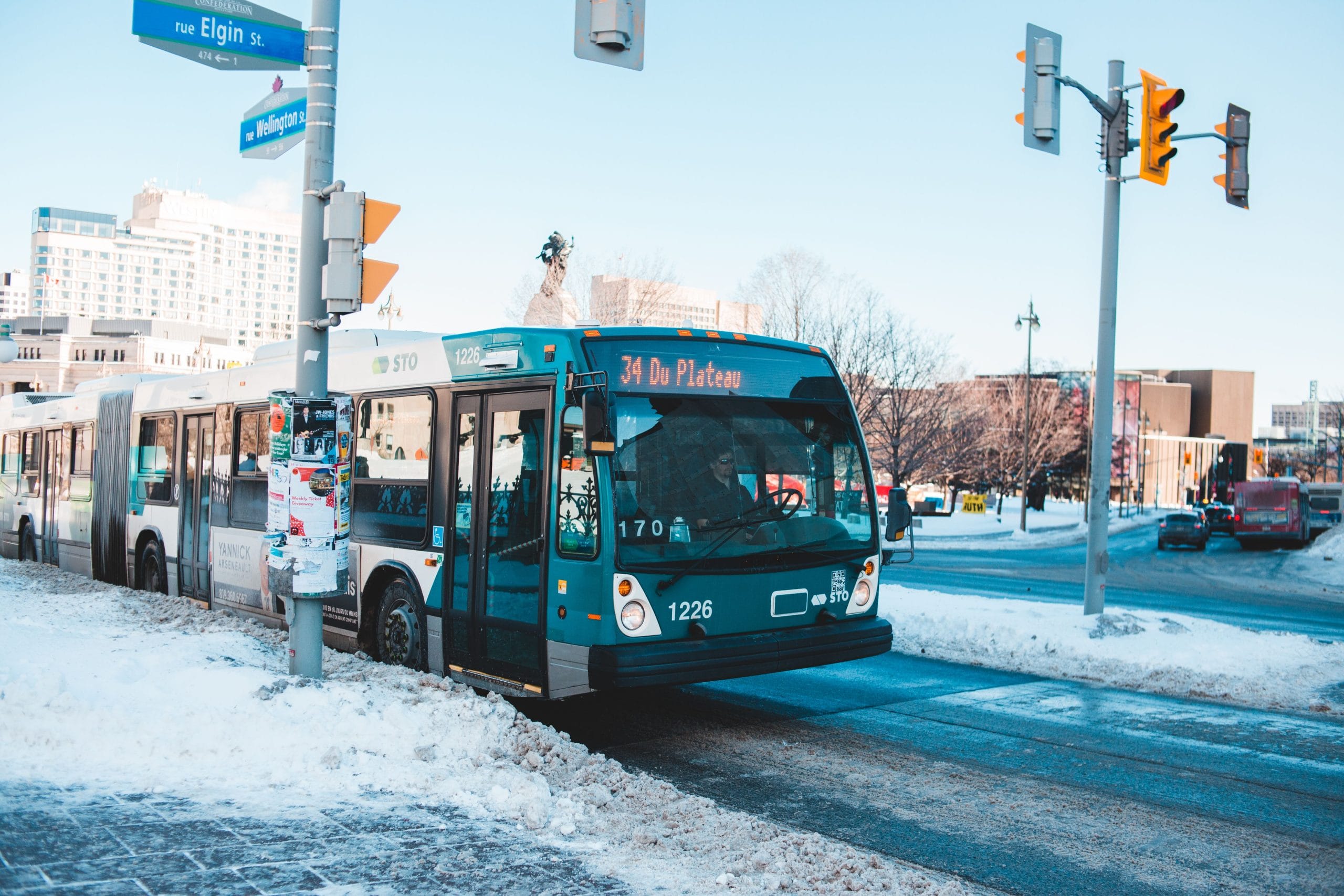 Urban bus navigating snowy streets at a city intersection during daytime winter.